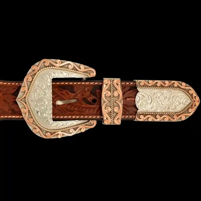 A custom western three piece belt buckle set featuring an engraved silver base with copper edge accents 
